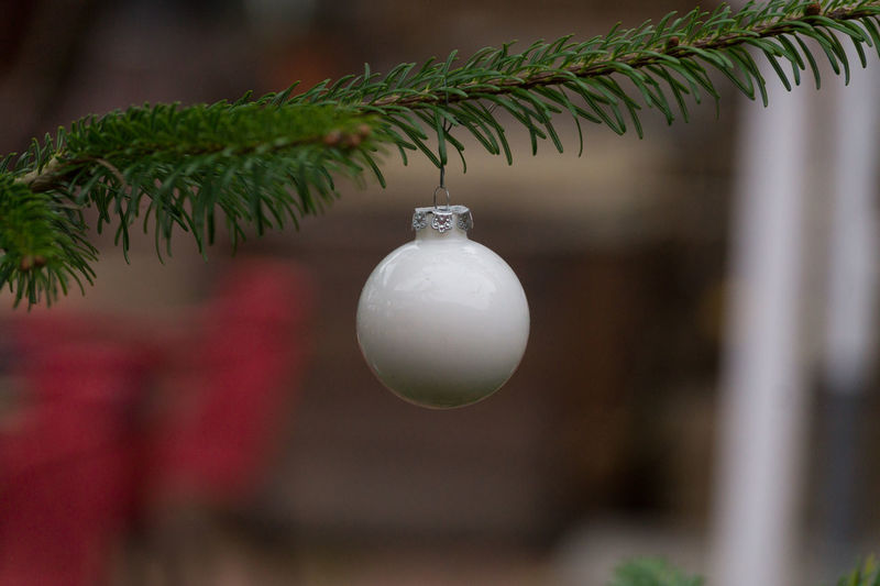 White bauble hanging from christmas tree