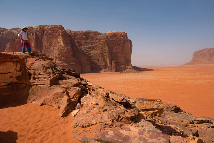 Woman standing on rock at desert against sky