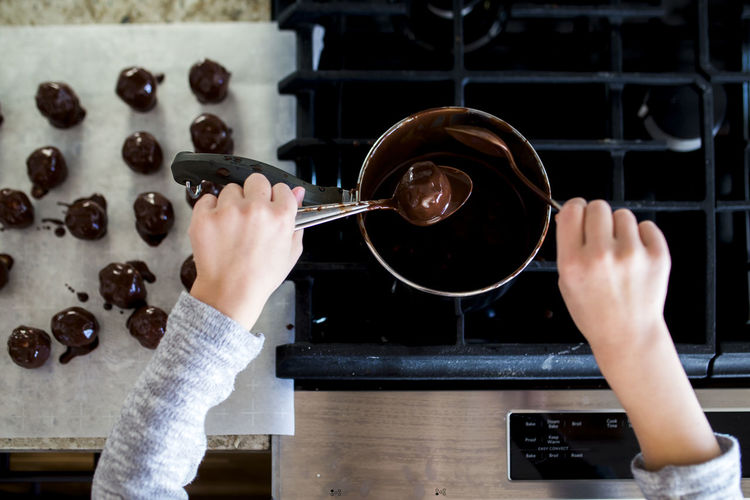 Cropped hands of girl making chocolate truffles in kitchen at home
