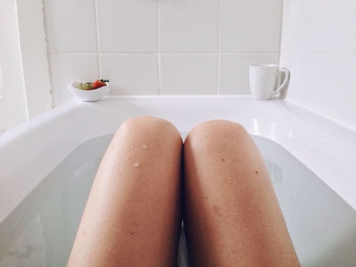 Midsection of woman bathing in bathtub
