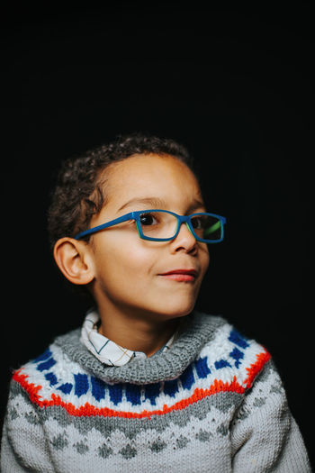 Portrait of boy wearing sunglasses against black background