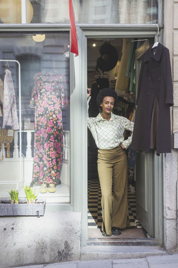 African female owner with hand on hip standing at doorway in store