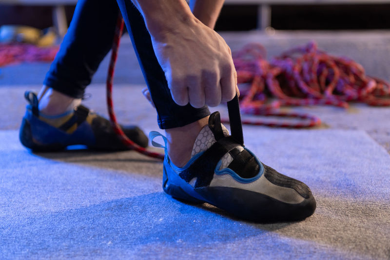 Unrecognizable athlete fastening climbing shoes