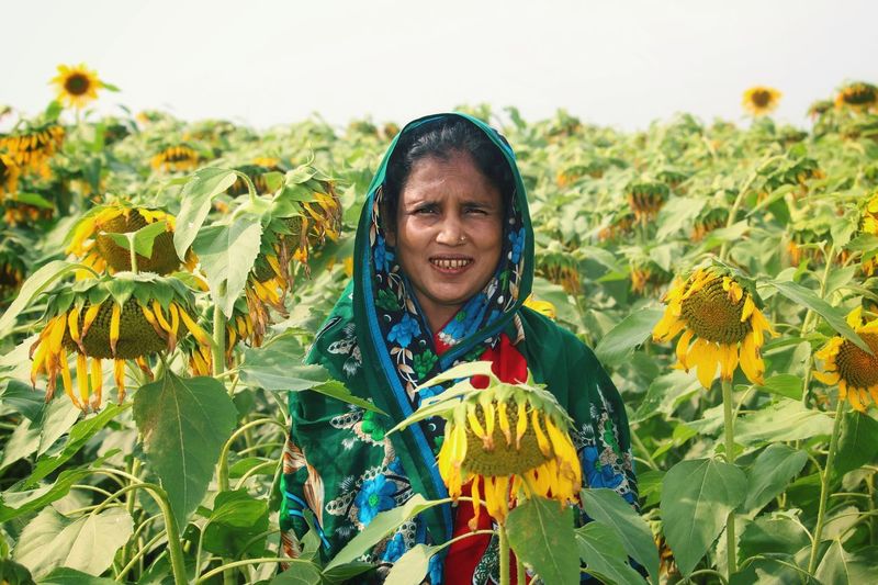 Portrait of smiling girl with sunflower amidst plants