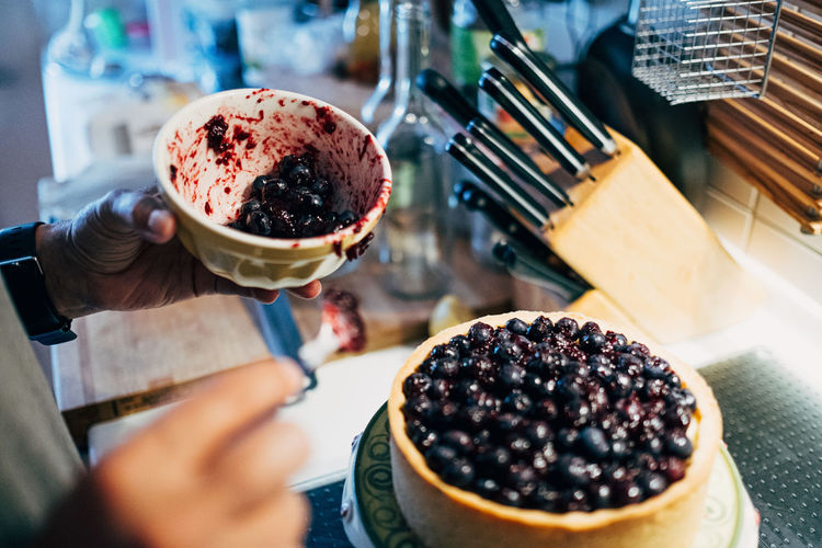 Close-up of hand preparing blueberry cheese cake