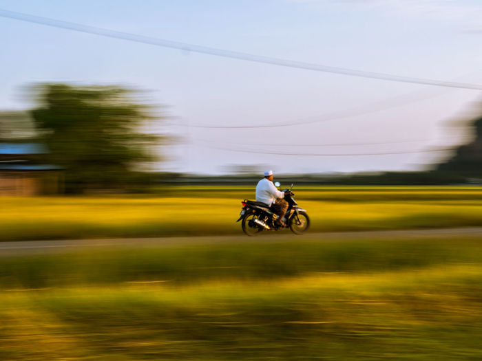 Blurred motion of man riding motorcycle against sky