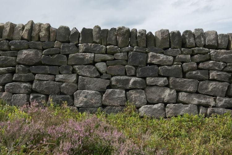 Stone wall on field against sky