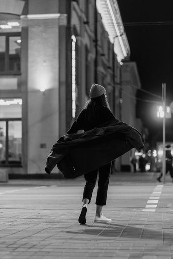 Rear view of woman walking on sidewalk at night