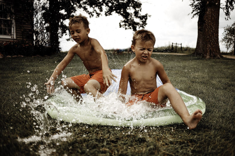 Brothers playing in wading pool at yard