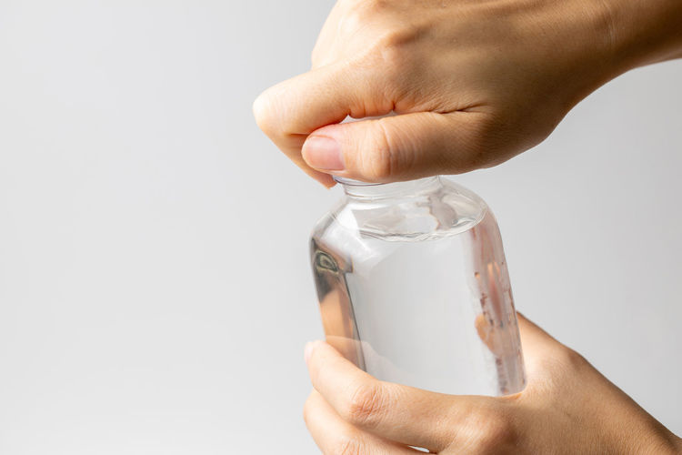 Midsection of person holding bottle against white background