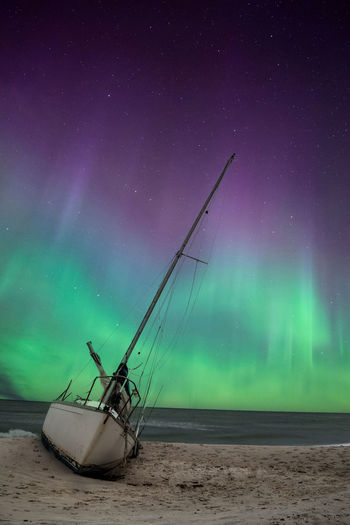 Aurora borealis over a shipwreck off the coast of uttakleiv beach in norway