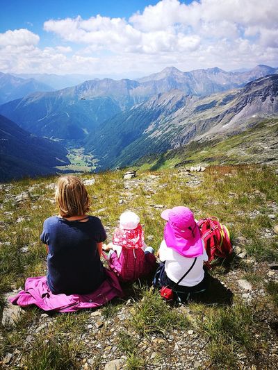 High angle view of mother with daughters sitting on cliff against sky