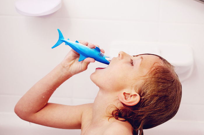 Wet shirtless boy playing with toy in bathroom