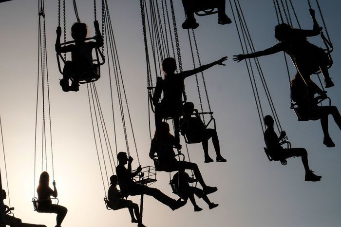 LOW ANGLE VIEW OF SILHOUETTE PEOPLE IN AMUSEMENT PARK AGAINST SKY
