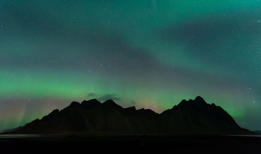 Scenic view of rocky mountains against aurora borealis in sky at night