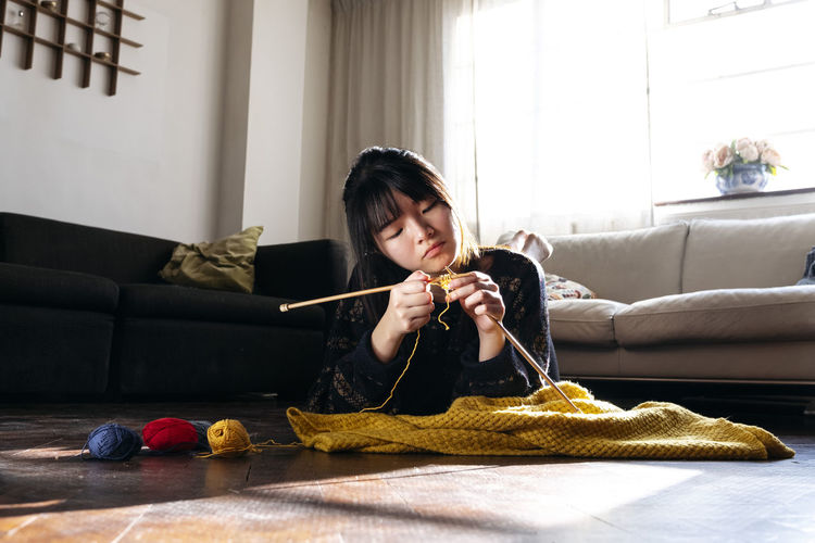 Woman knitting and relaxing on floor at home