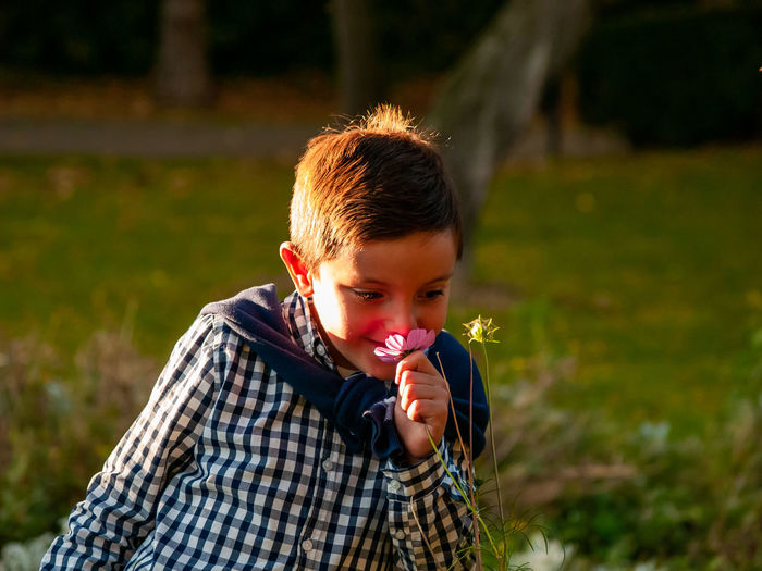 Boy smelling flower in garden
