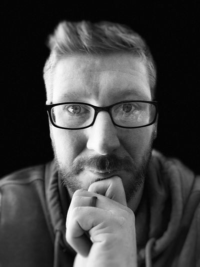 Portrait of man wearing eyeglasses against black background