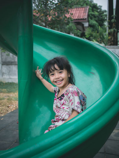 Portrait of cute smiling girl sliding in playground