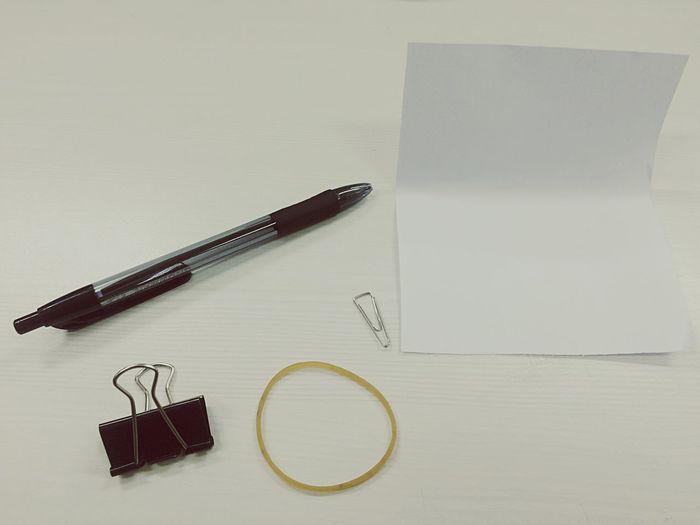 High angle view of paper with pen and binder clip on desk
