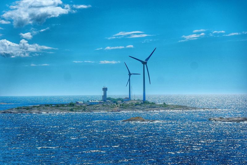 Wind turbines against calm blue sea
