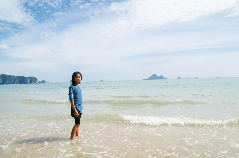 Portrait of teenage girl standing against sea at beach