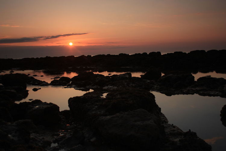 Scenic view of rocks against sky during sunset