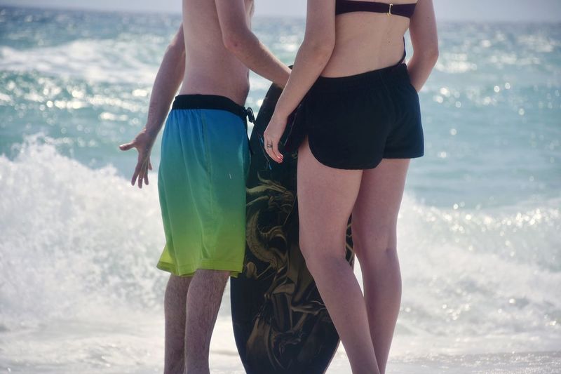 Midsection of couple standing at beach