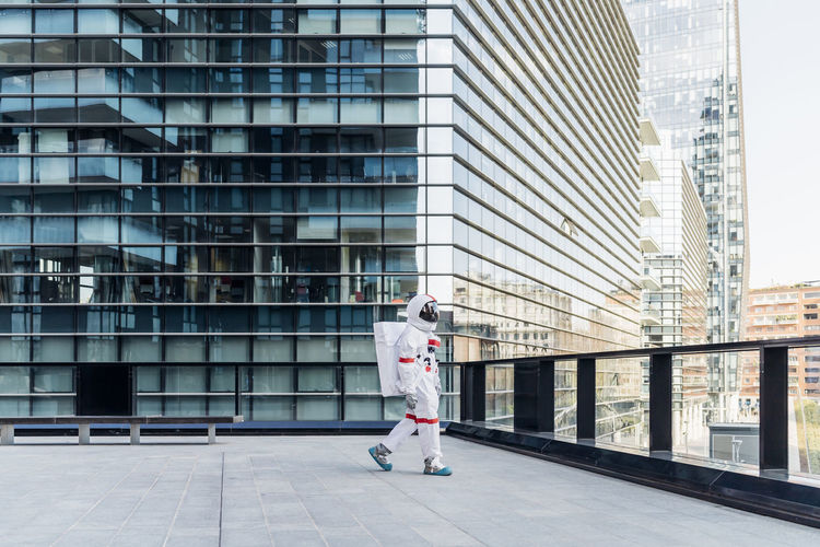 Male astronaut wearing space suit walking on rooftop
