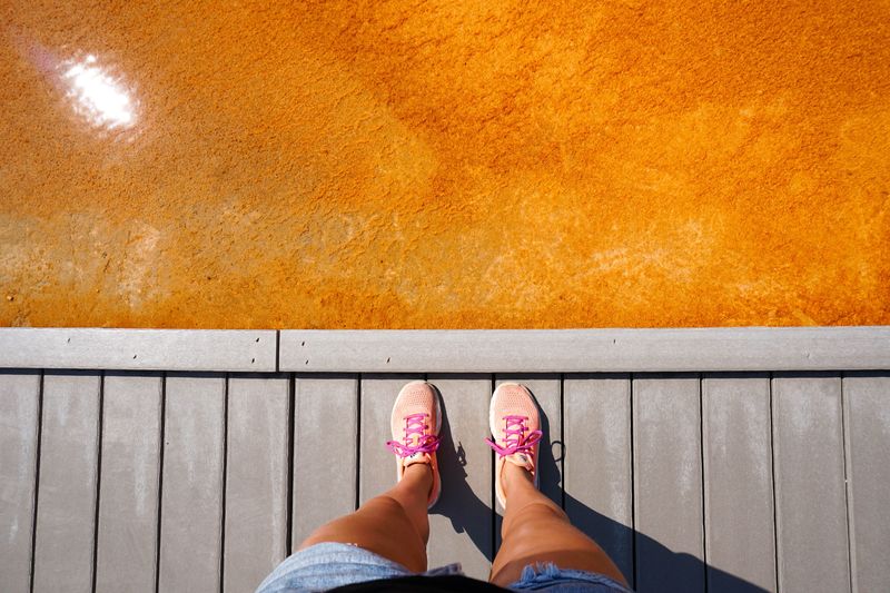 Low section of woman standing on jetty by orange water
