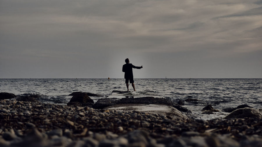 Silhouette man on beach against sky
