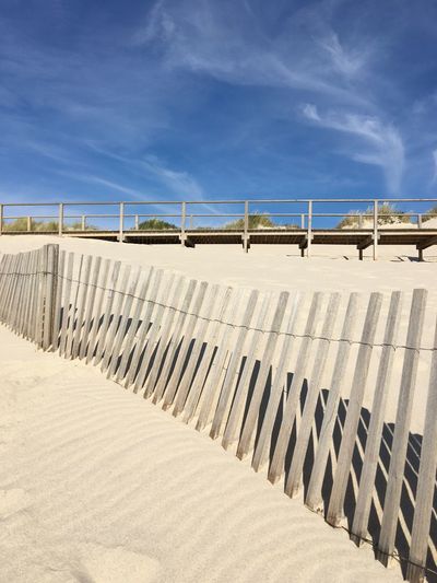 View of fence on beach against blue sky