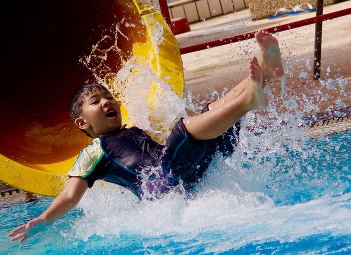 Full length of boy enjoying on water slide in pool