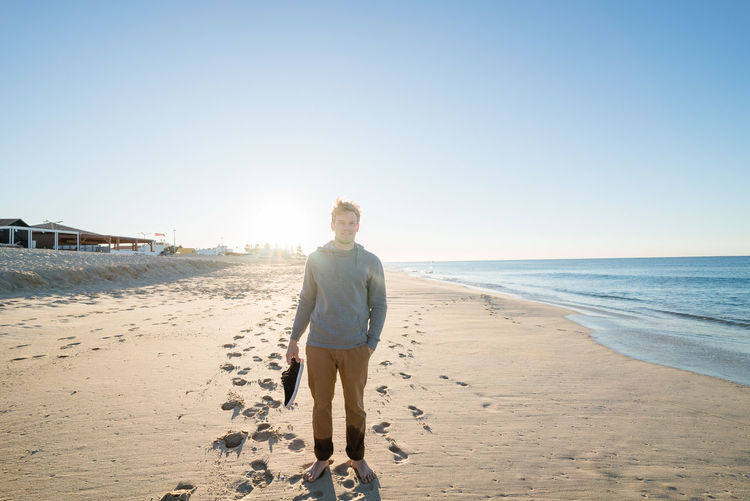 Portrait of man standing at beach against sky