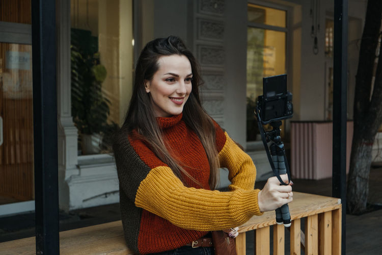 Smiling woman vlogging while standing outdoors