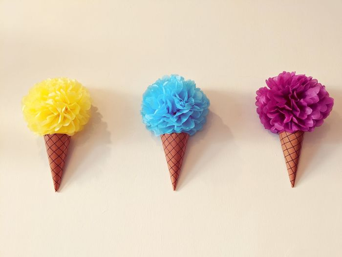 Multi colored artificial ice cream cones on beige background