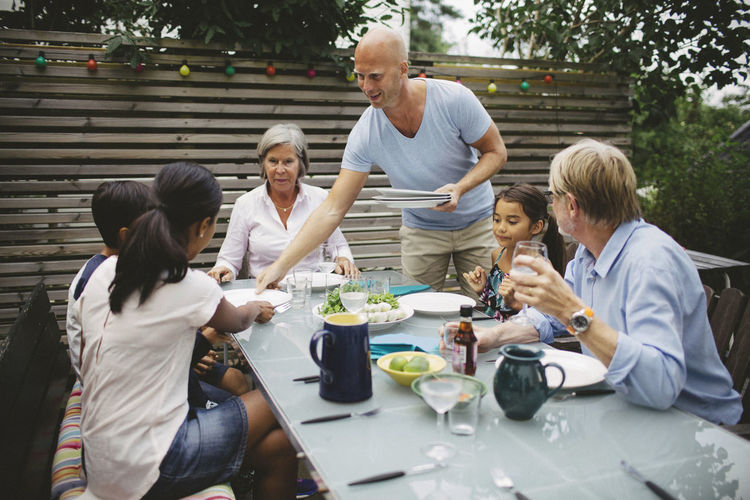 Man serving food to family at outdoor dining table