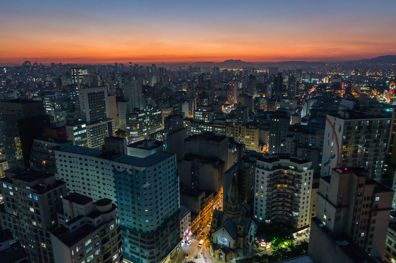 Aerial view of illuminated cityscape against sky during sunset