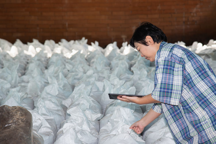 Woman checking sack while holding digital tablet