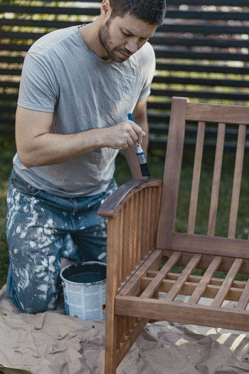 Man painting bench in garden