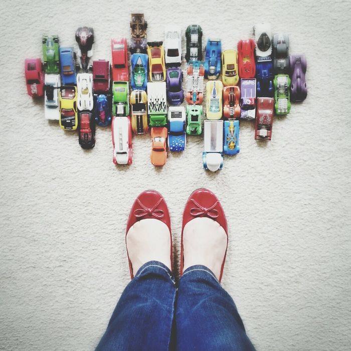 Low section of girl with toy cars on floor