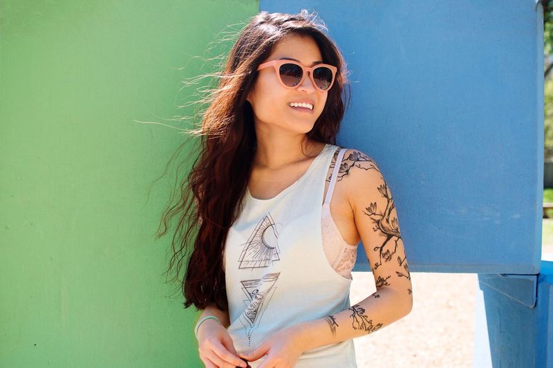 Portrait of smiling young woman wearing sunglasses standing outdoors