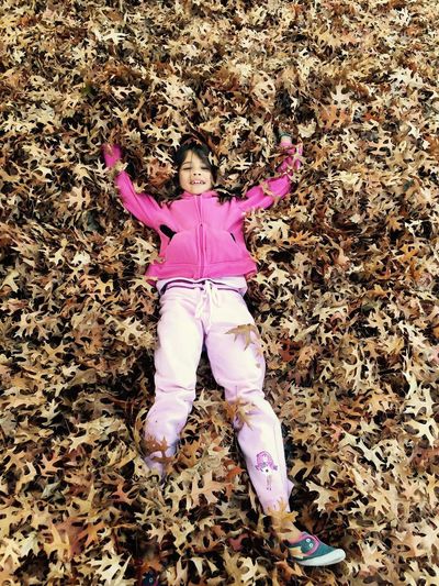 High angle portrait of girl lying down on leaves