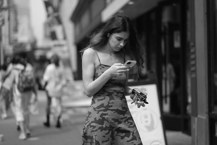 Woman looking at camera while standing on mobile phone