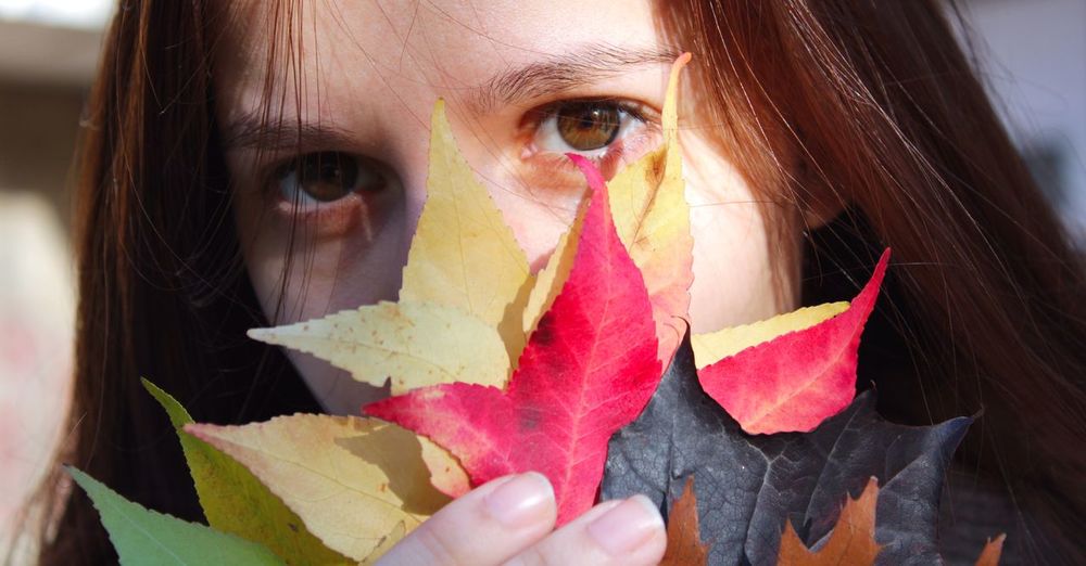 Close-up portrait of woman holding autumn leaves