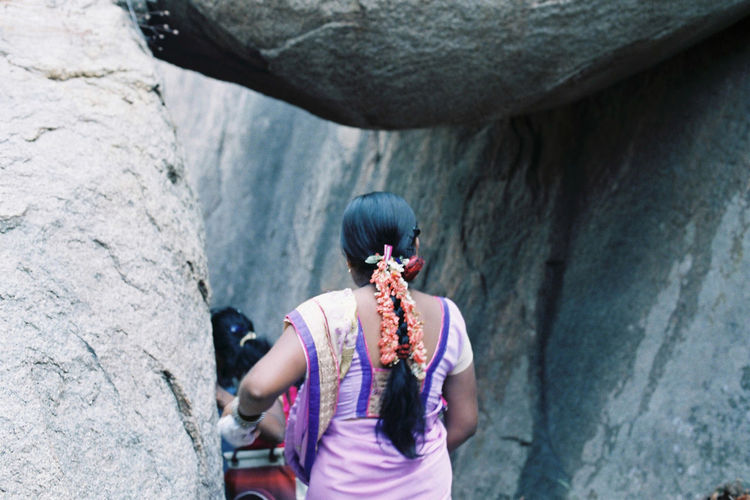 Rear view of woman wearing sari walking by rock formations