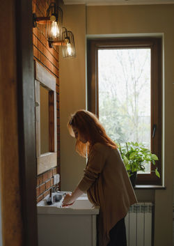Personal hygiene in bathroom. ginger haired woman taking care of skin at home. washing hands and
