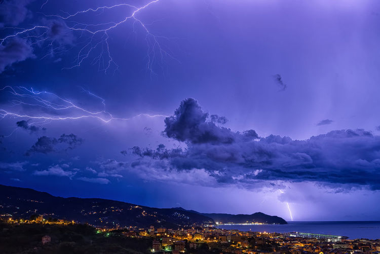 Aerial view of illuminated city lightning in dramatic sky at night