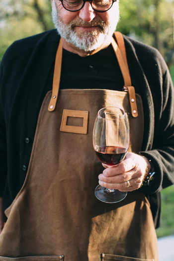Man in apron holding wine glass