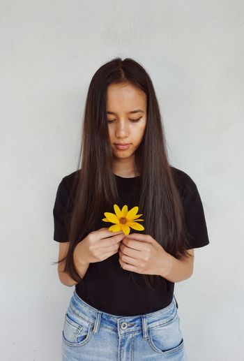Close-up of a beautiful young woman holding yellow flower